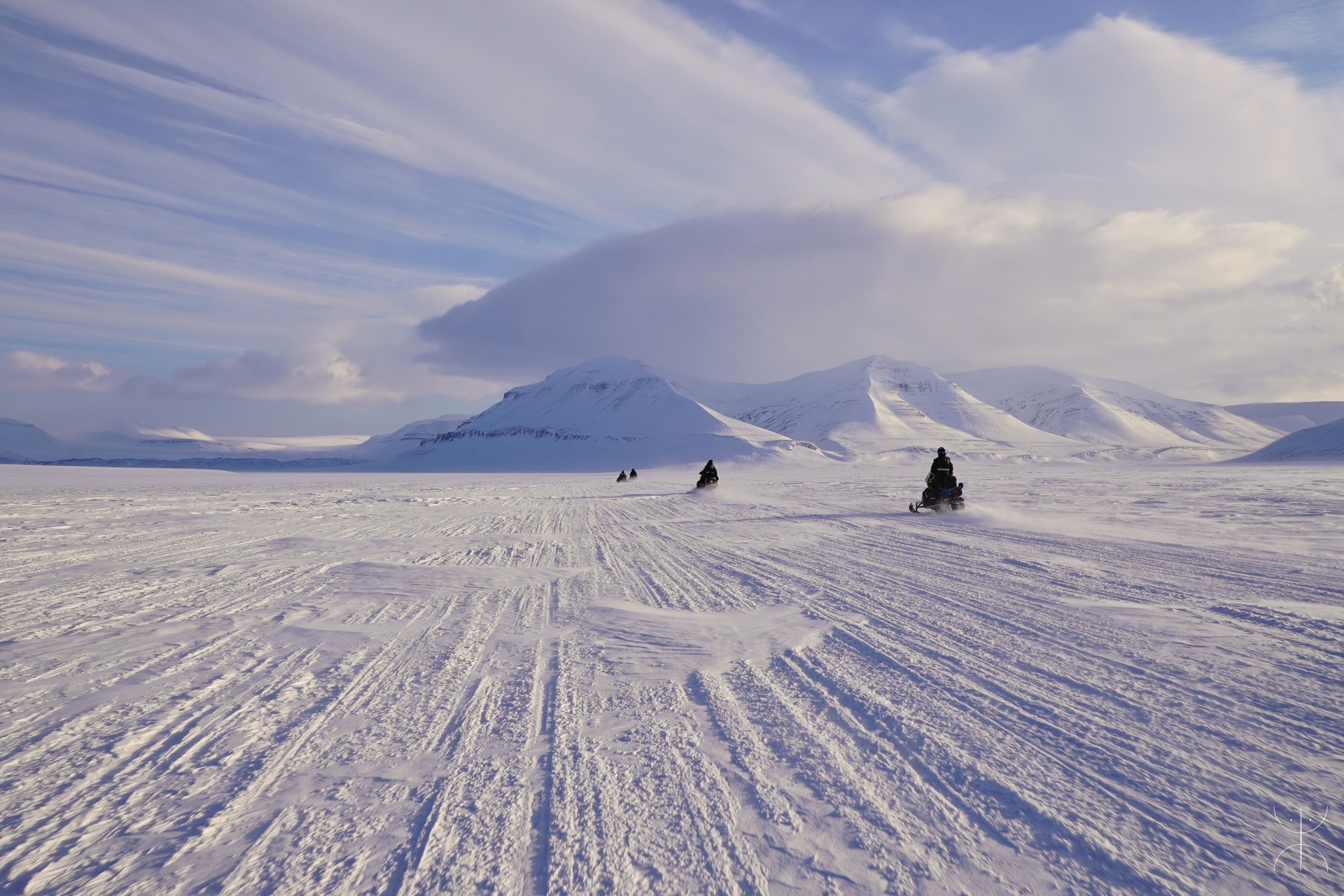 Guided snowmobile expedition crossing a frozen fjord in Svalbard
